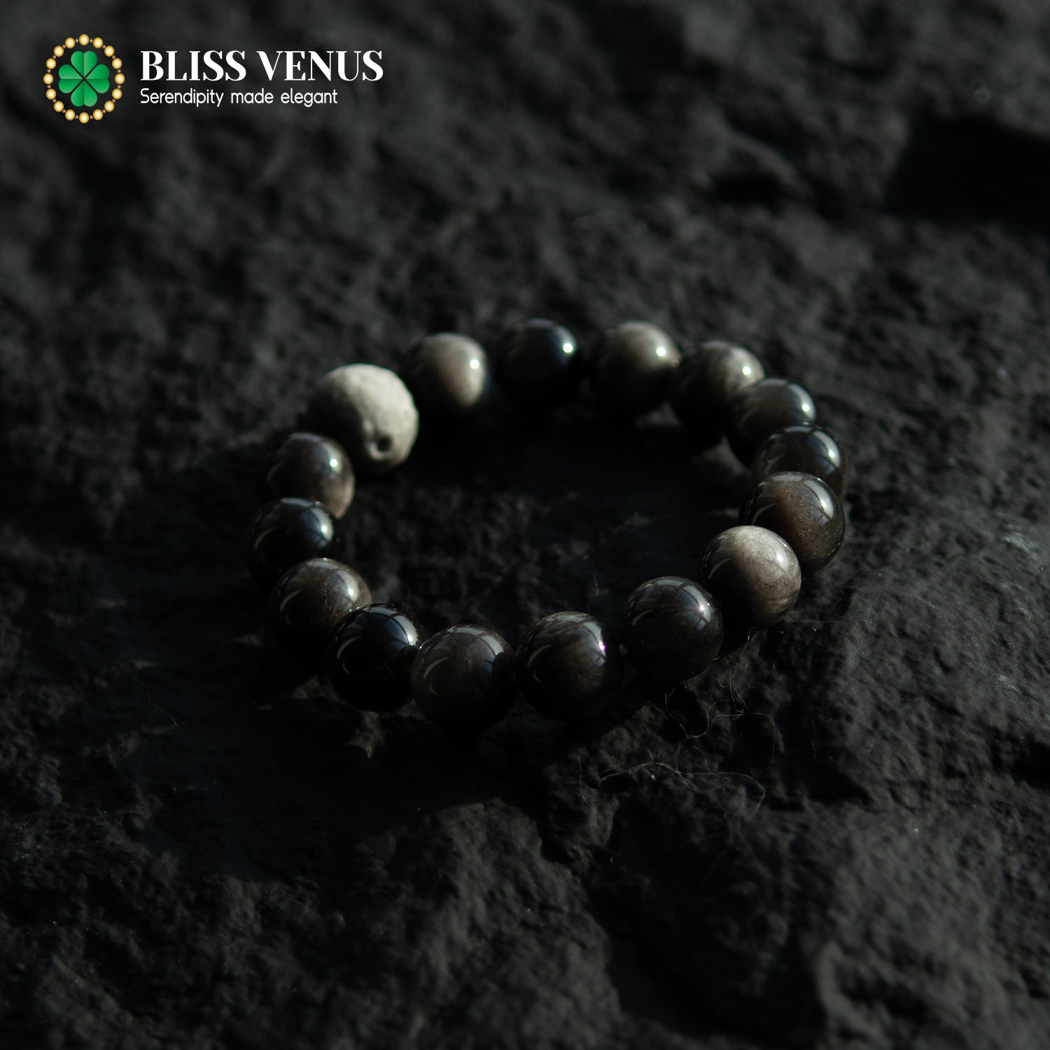 Close-up of black obsidian bracelet showing natural silver and black stone texture and luster